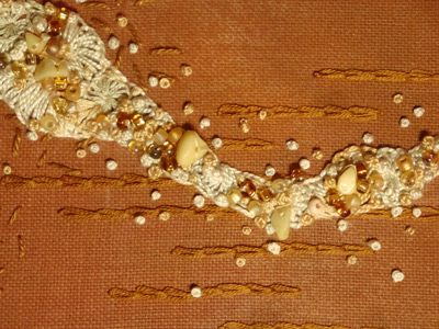 Image - cream stitching and beading on rust, detail